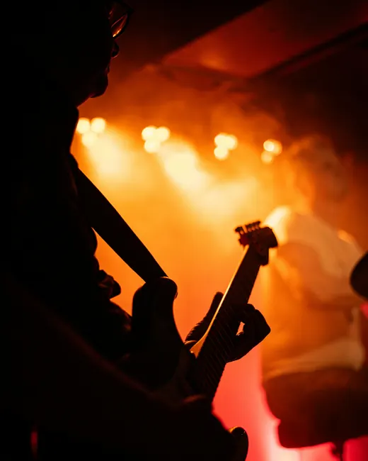 Un guitariste en contre-jour devant des projecteurs orange